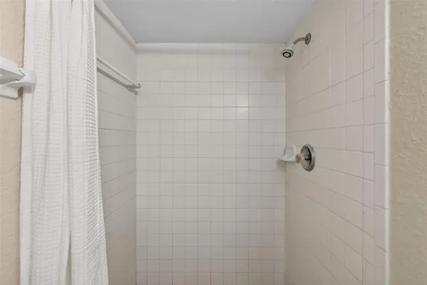 a view of an empty room with wooden floor and a ceiling fan