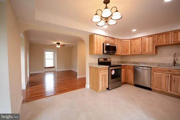 a kitchen with stainless steel appliances granite countertop a stove top oven a sink dishwasher a dining table and chairs with wooden floor