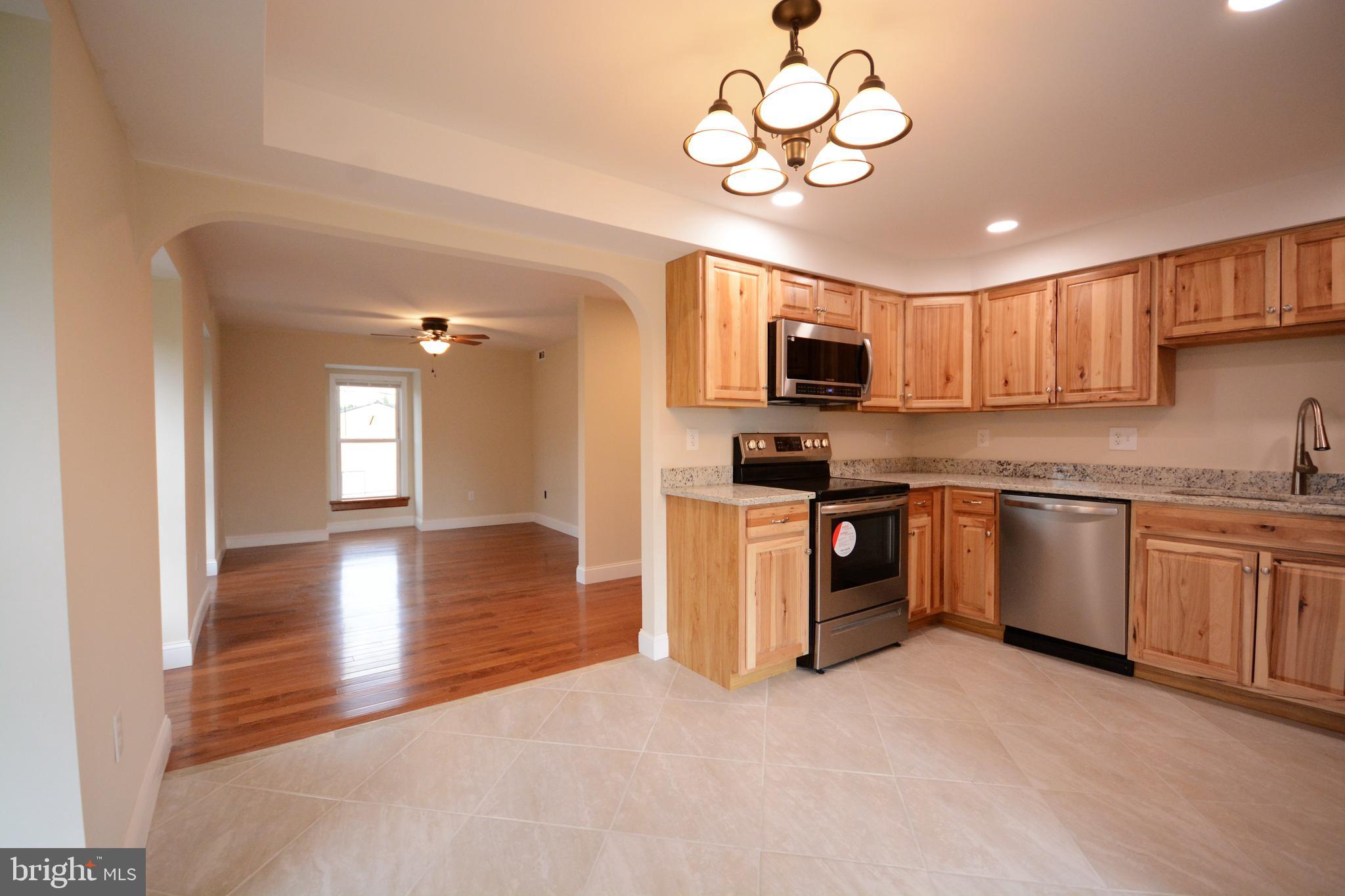 a kitchen with stainless steel appliances granite countertop a stove top oven a sink dishwasher a dining table and chairs with wooden floor