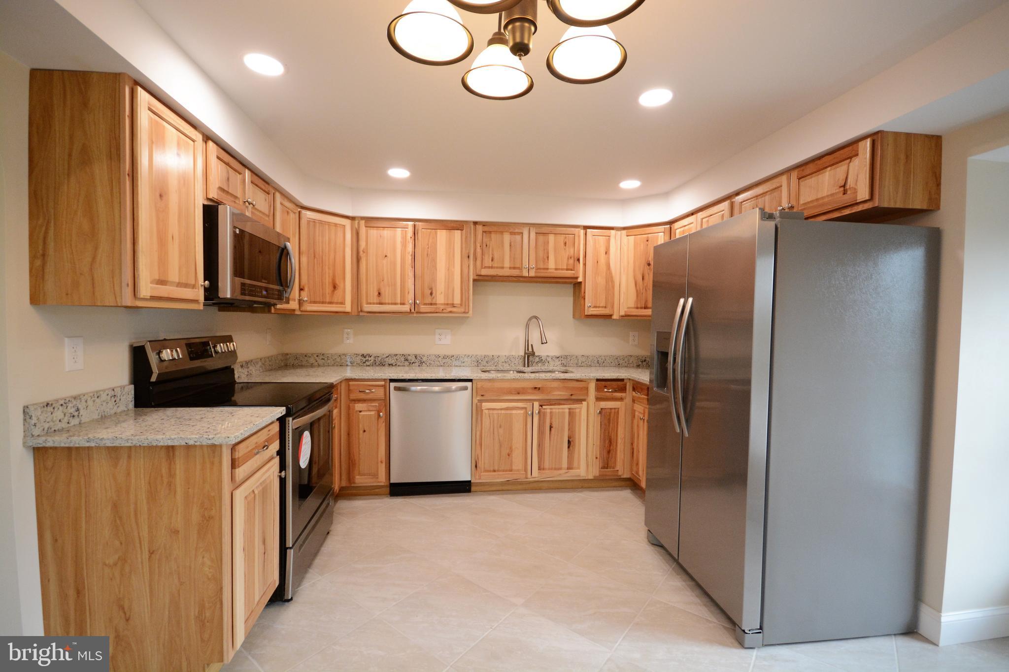 12439 Old Frederick Road, Unit 6 Thurmont, MD 21788 - Photo 2 of 15 a kitchen with stainless steel appliances granite countertop a refrigerator a stove top oven a sink and dishwasher