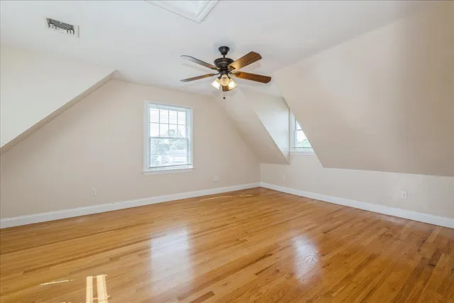 an empty room with wooden floor fan and windows