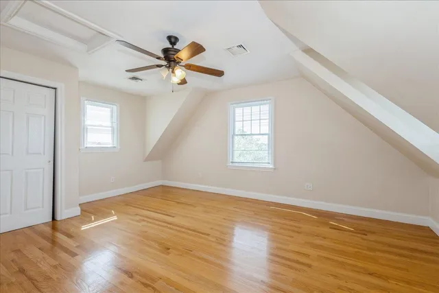 an empty room with wooden floor fan and windows