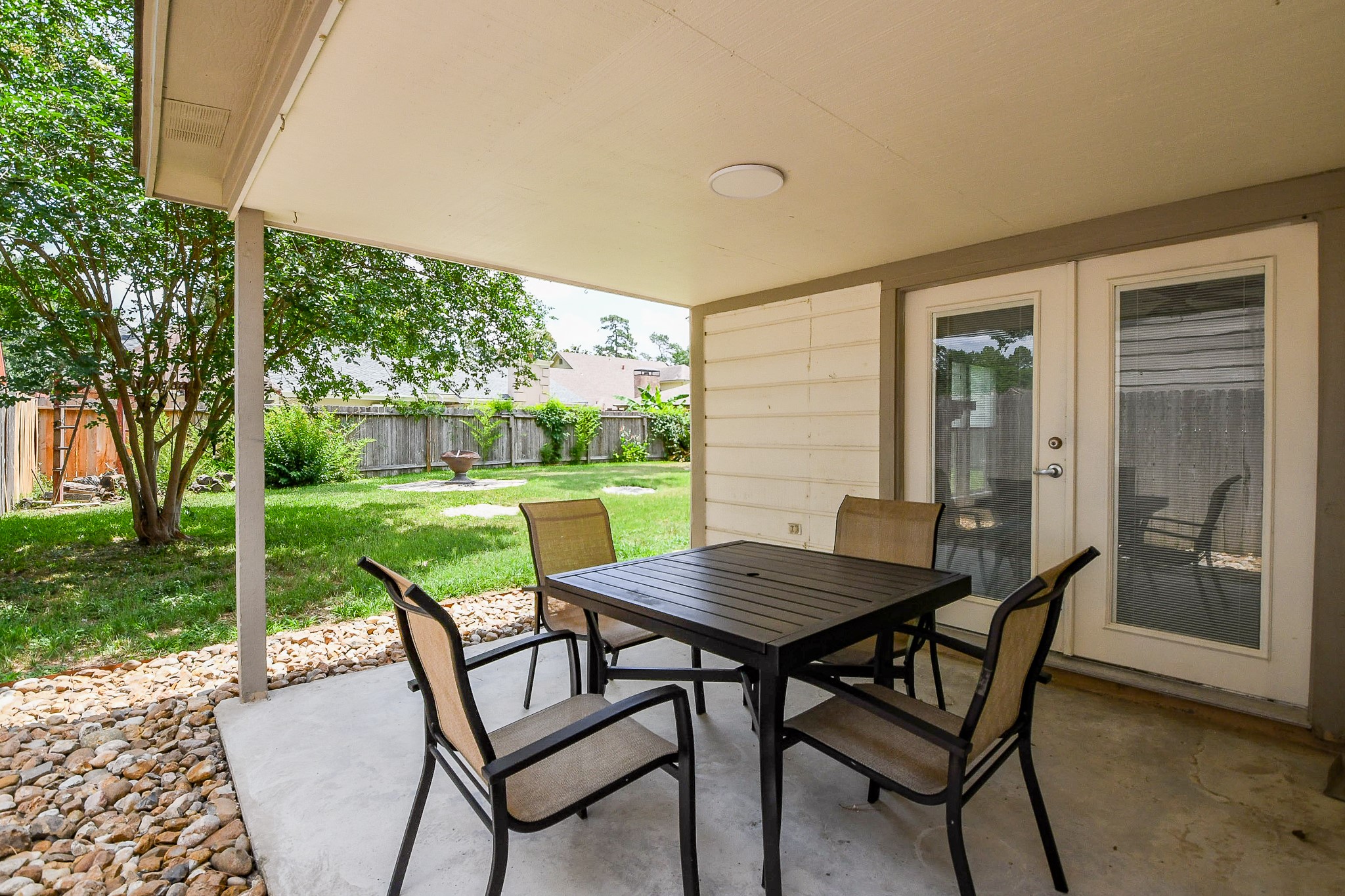 19522 Dianeshire Drive Spring, TX 77388 - Photo 26 of 32 Cozy covered patio with seating area, overlooking a spacious, well-maintained backyard with lush greenery and a privacy fence—ideal for outdoor relaxation and entertainment.