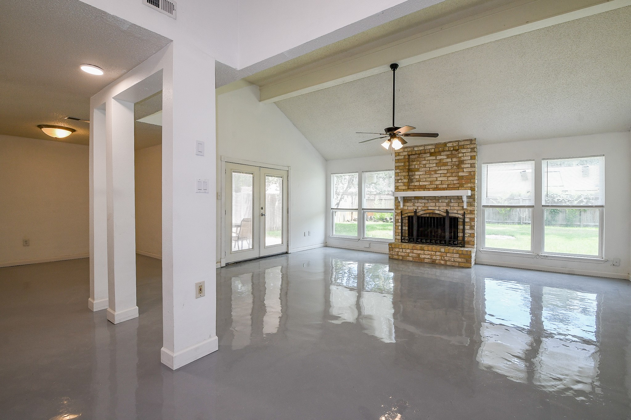 19522 Dianeshire Drive Spring, TX 77388 - Photo 4 of 32 This spacious living area features high ceilings, a brick fireplace, and large windows providing plenty of natural light. The floors are sleek and polished, and there's access to the backyard through French doors. Ideal for entertaining and relaxation.