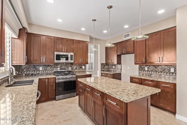a kitchen with kitchen island granite countertop wooden cabinets and a chandelier