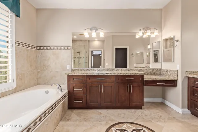 a bathroom with a granite countertop double vanity sink a mirror and a bathtub