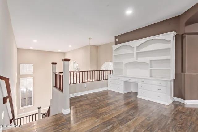 a view of an empty room with wooden floor and a ceiling fan