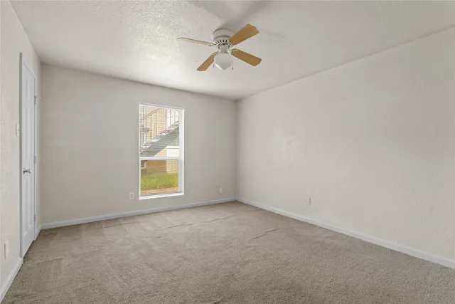 an empty room with ceiling fan and windows