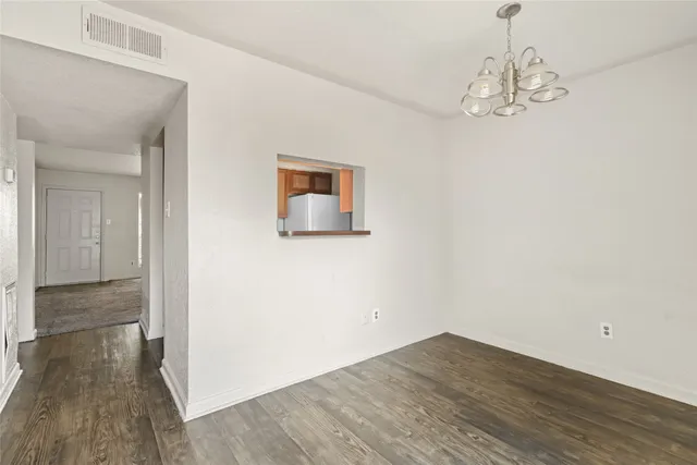 a view of a hallway with wooden floor and a chandelier