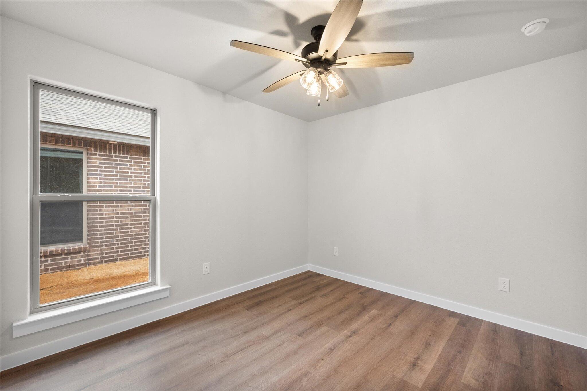 3022 140th Street Lubbock, TX 79423 - Photo 17 of 20 an empty room with wooden floor fan and windows