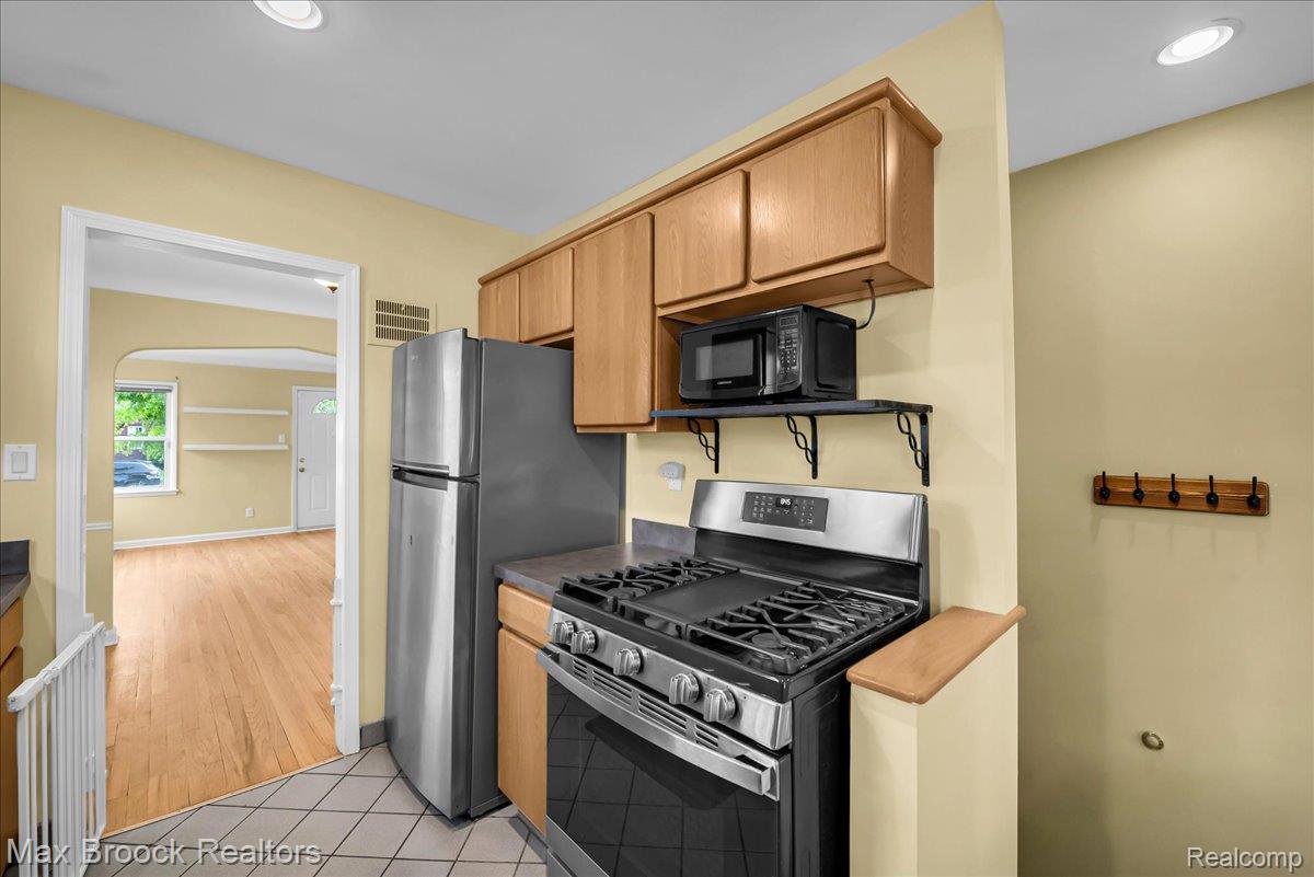 1311 Harvard Road Berkley, MI 48072 - Photo 13 of 29 Kitchen with stainless steel gas range oven, light tile patterned floors, black microwave, dark countertops, and recessed lighting