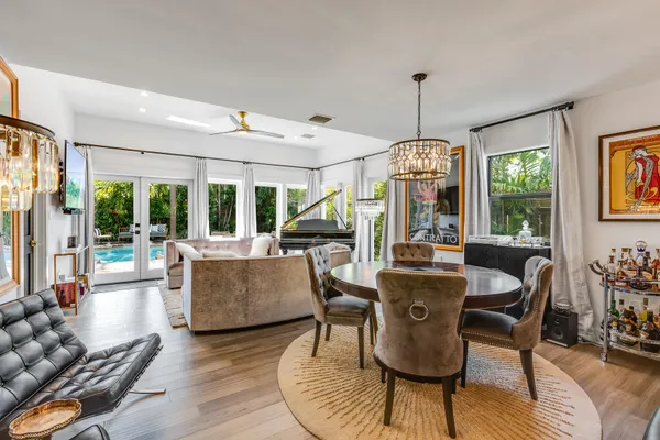 a dining room with furniture wooden floor a chandelier and windows