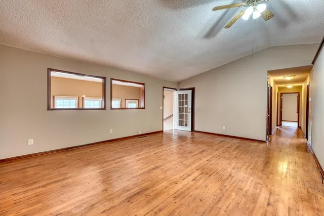 a view of empty room with wooden floor and fan