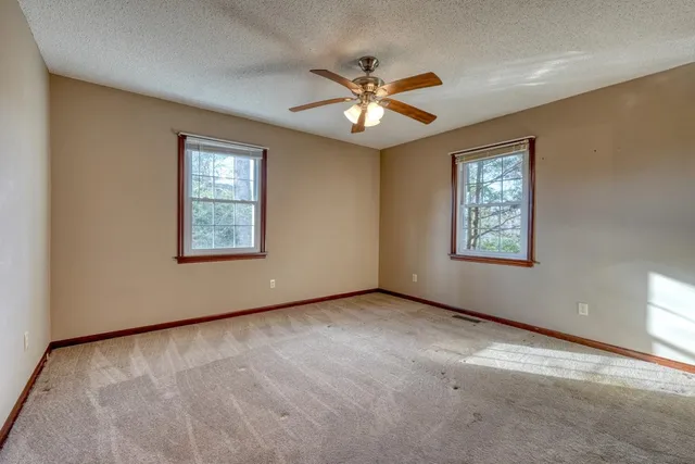 an empty room with windows and fan