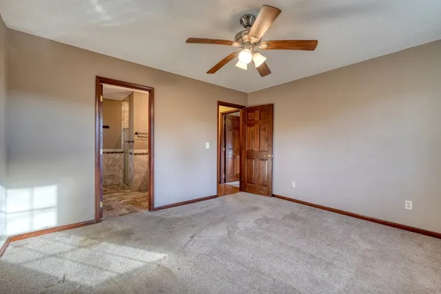 a view of an empty room with a chandelier fan