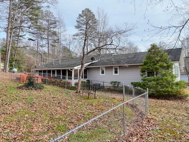a backyard of a house with large trees and wooden fence
