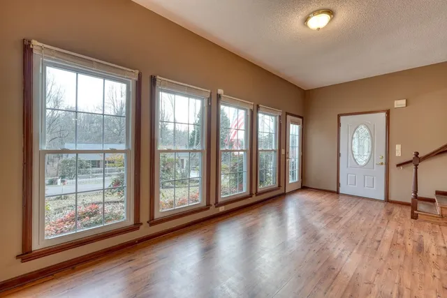 a view of an empty room with a window and wooden floor
