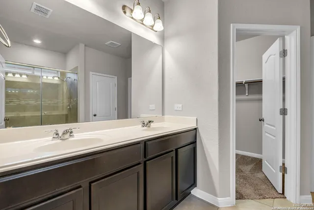 a bathroom with a double vanity sink a mirror and a shower