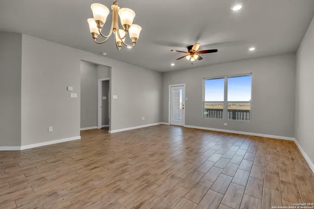 a view of an empty room with a window and wooden floor