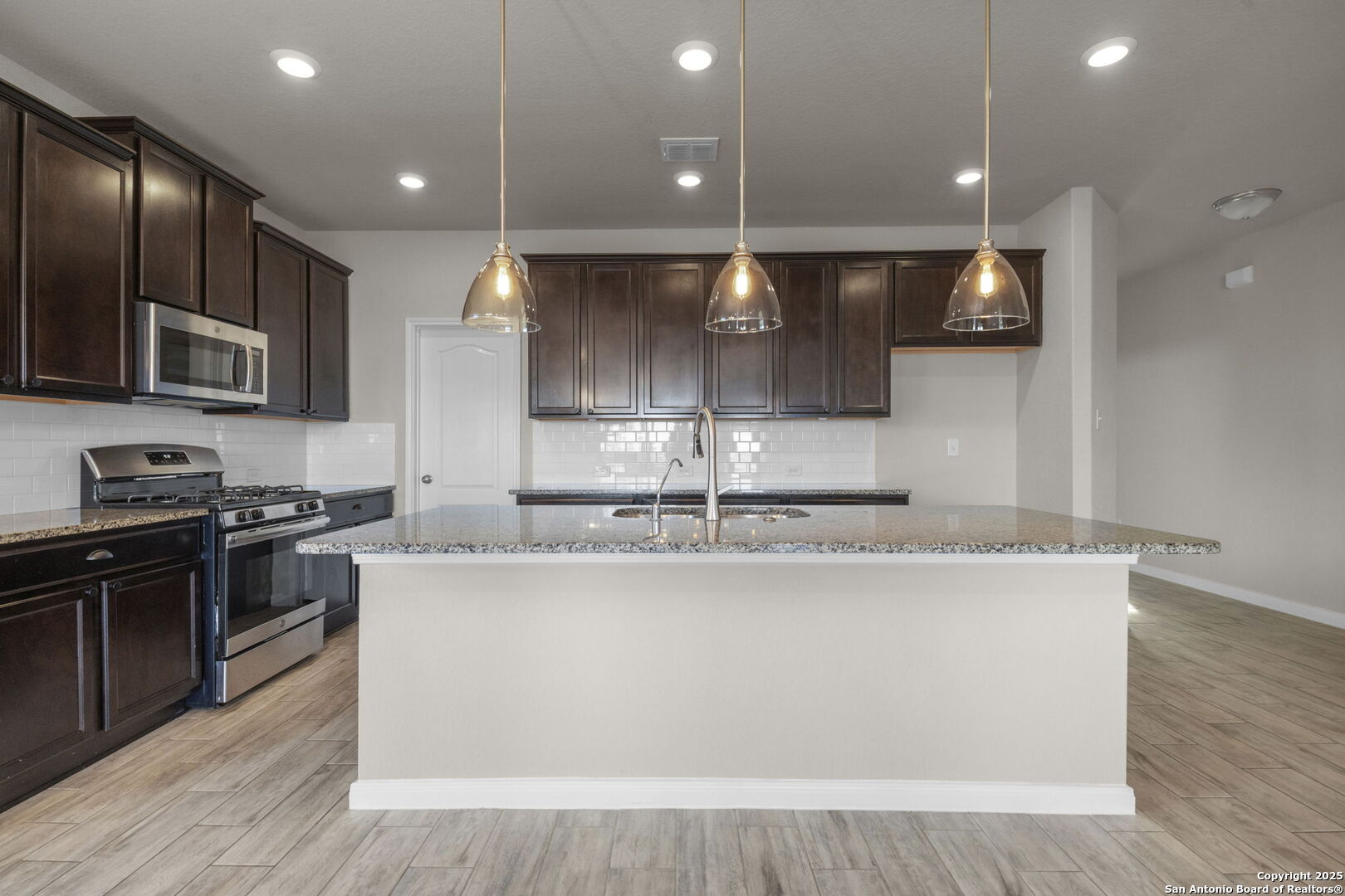 10411 Francisco Way Converse, TX 78109 - Photo 8 of 25 a large kitchen with stainless steel appliances granite countertop a stove a sink and a microwave