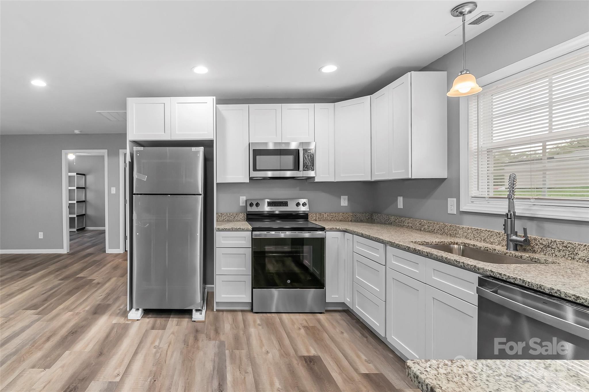 391 Springs East Road Lincolnton, NC 28092 - Photo 13 of 26 a kitchen with a sink a refrigerator and a stove top oven with wooden floor