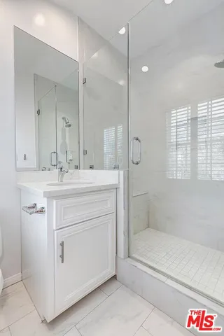 a bathroom with a shower sink vanity and mirror