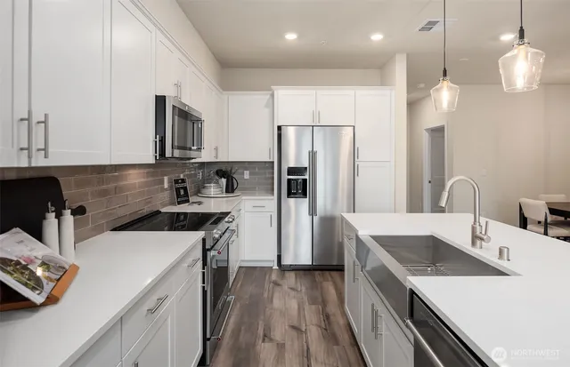 a kitchen that has a lot of cabinets a sink and wooden floor