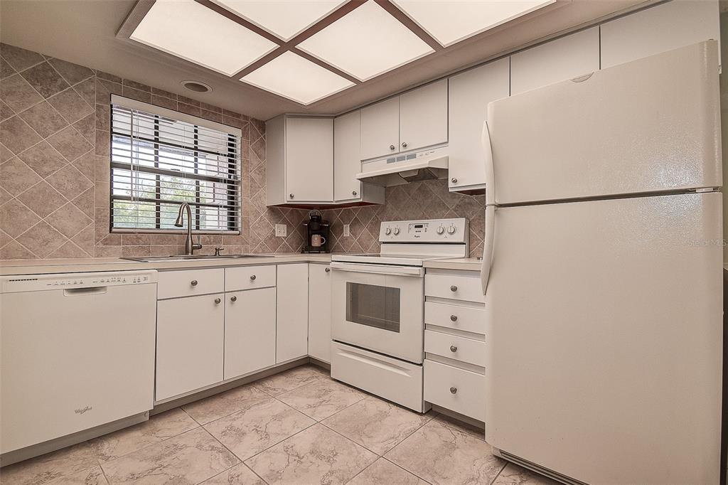 12900 Vonn Road, Unit C202 Largo, FL 33774 - Photo 5 of 38 a kitchen with white cabinets and white appliances
