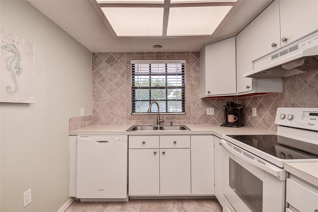 12900 Vonn Road, Unit C202 Largo, FL 33774 - Photo 7 of 38 a kitchen with granite countertop white cabinets and white appliances