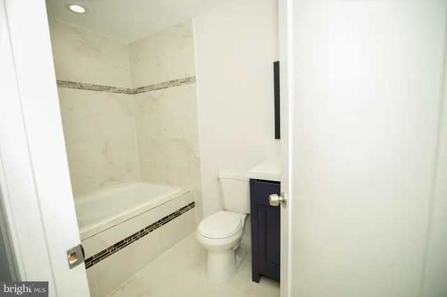 a bathroom with a granite countertop bathtub shower sink mirror and toilet