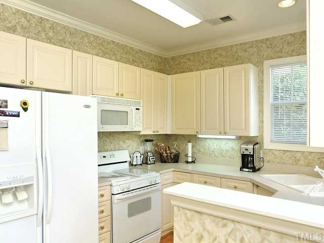 8321 Amber Leaf Court Raleigh, NC 27612 - Photo 8 of 25 Light and bright eat-in kitchen with under-cabinet lighting, corner sink, lots of cabinet space, gas range and microwave vent hood.