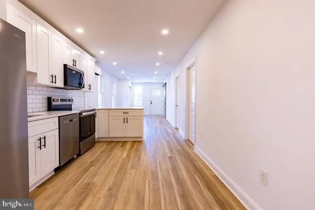 a large kitchen with stainless steel appliances granite countertop a lot of cabinets and wooden floor