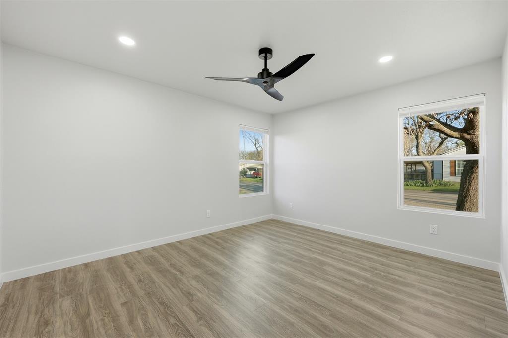 502 Madison Street Cleburne, TX 76033 - Photo 22 of 30 an empty room with wooden floor ceiling fan and windows