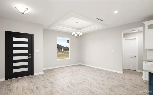 an empty room with wooden floor cabinet and windows