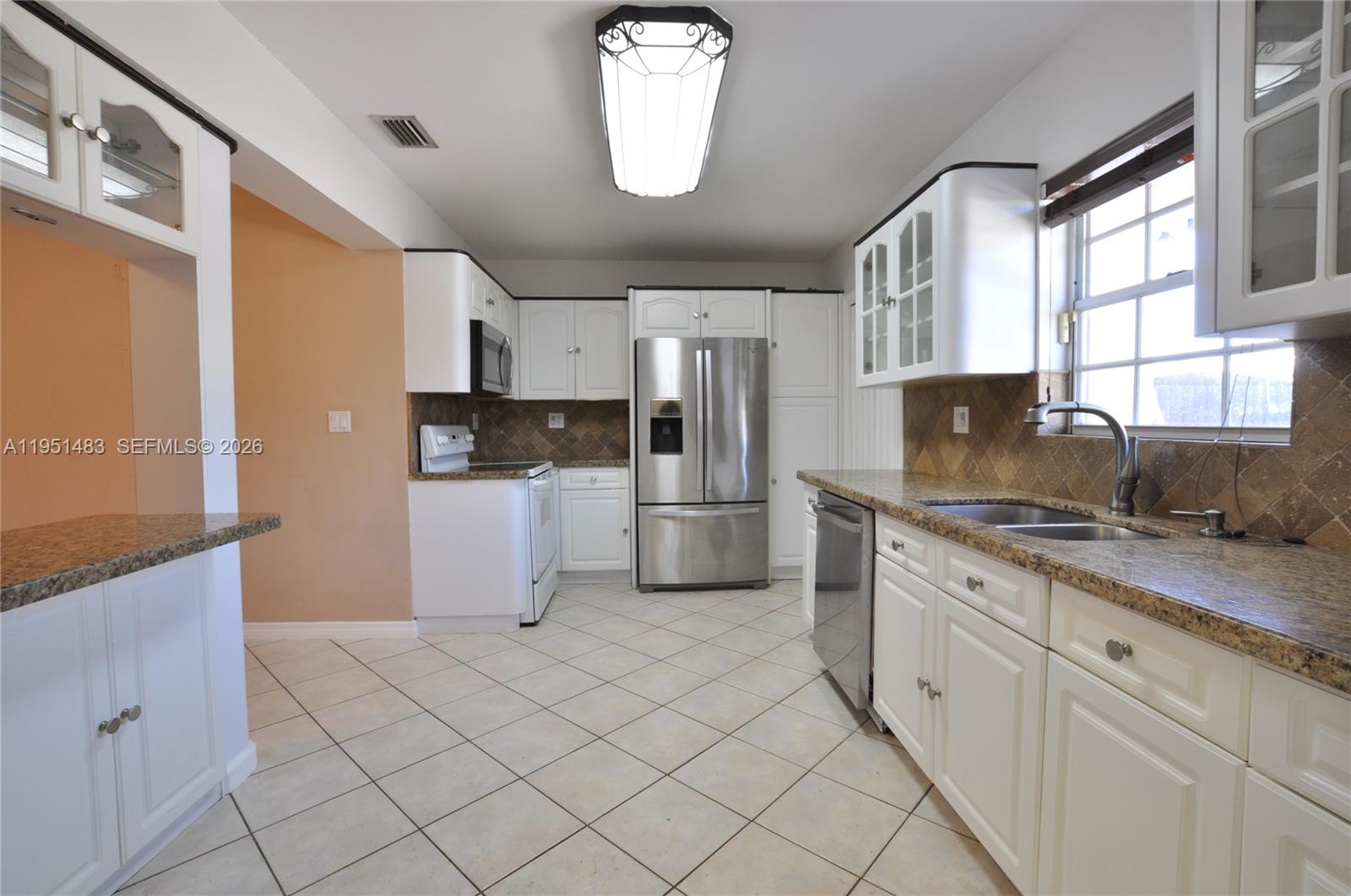 10502 Southwest 77th Court, Unit 10502 Pinecrest, FL 33156 - Photo 8 of 33 a kitchen with granite countertop white cabinets and white appliances