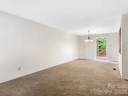 an empty room with windows and chandelier fan