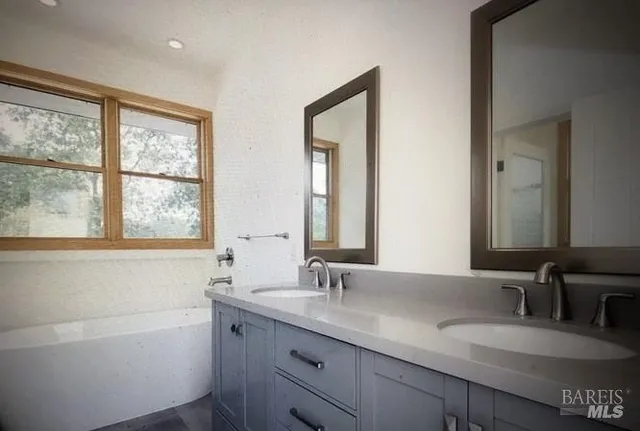 a bathroom with a granite countertop sink a large mirror a and a window