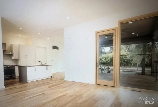 an empty room with wooden floor and a kitchen