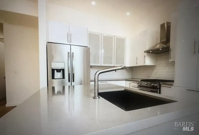 a kitchen with granite countertop a refrigerator and a stove top oven