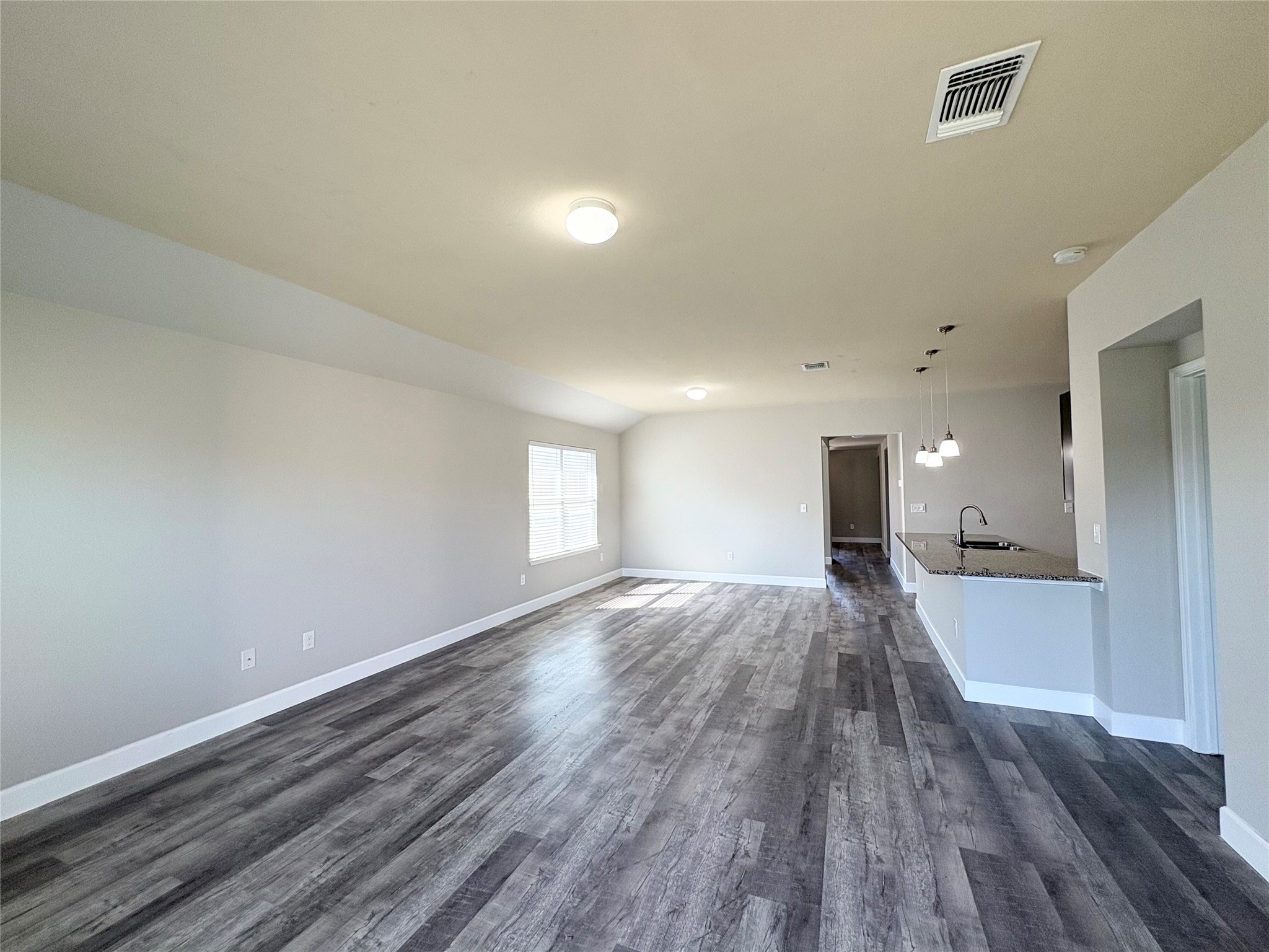 11708 Cambrian Road Manor, TX 78653 - Photo 10 of 31 Sun-filled open living area with rich wood-look flooring and a functional kitchen pass-through.