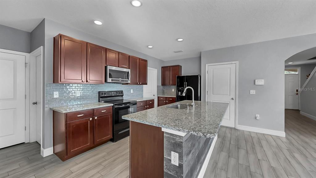 10237 Mangrove Well Road Sun City Center, FL 33573 - Photo 15 of 56 a kitchen with stainless steel appliances granite countertop a sink stove and refrigerator