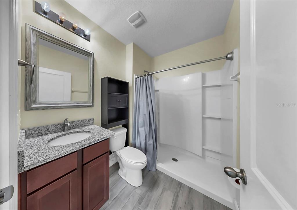 10237 Mangrove Well Road Sun City Center, FL 33573 - Photo 38 of 56 a bathroom with a granite countertop sink toilet and shower