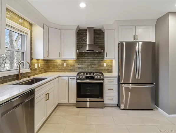 a kitchen with stainless steel appliances granite countertop a stove a sink and white cabinets