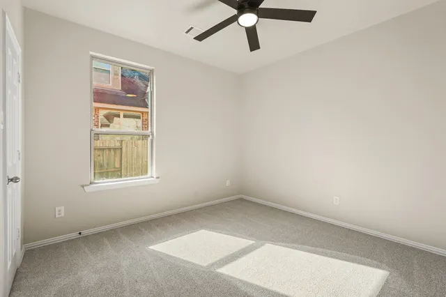 an empty room with a window and a ceiling fan