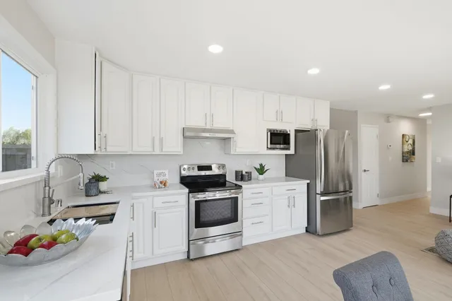a kitchen with a sink white cabinets and stainless steel appliances