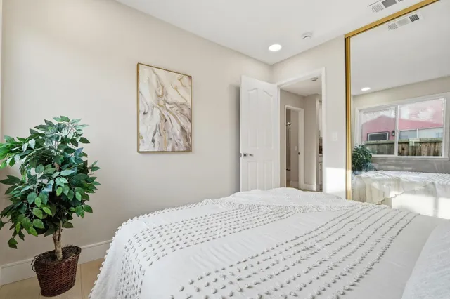 a bedroom with a large bed and a potted plant
