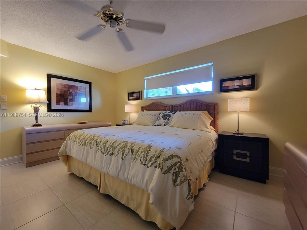 3774 Inverrary Boulevard, Unit 103P Lauderhill, FL 33319 - Photo 23 of 35 a bedroom with a bed and a chandelier