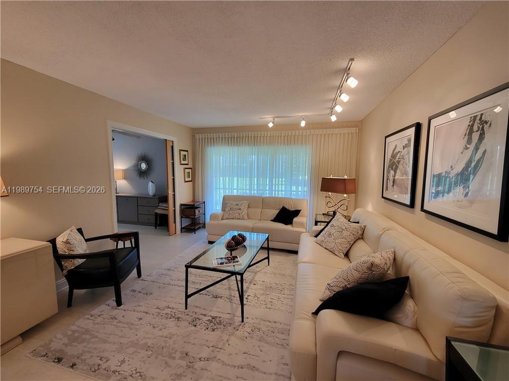 3774 Inverrary Boulevard, Unit 103P Lauderhill, FL 33319 - Photo 4 of 35 a living room with furniture and a painting on the wall