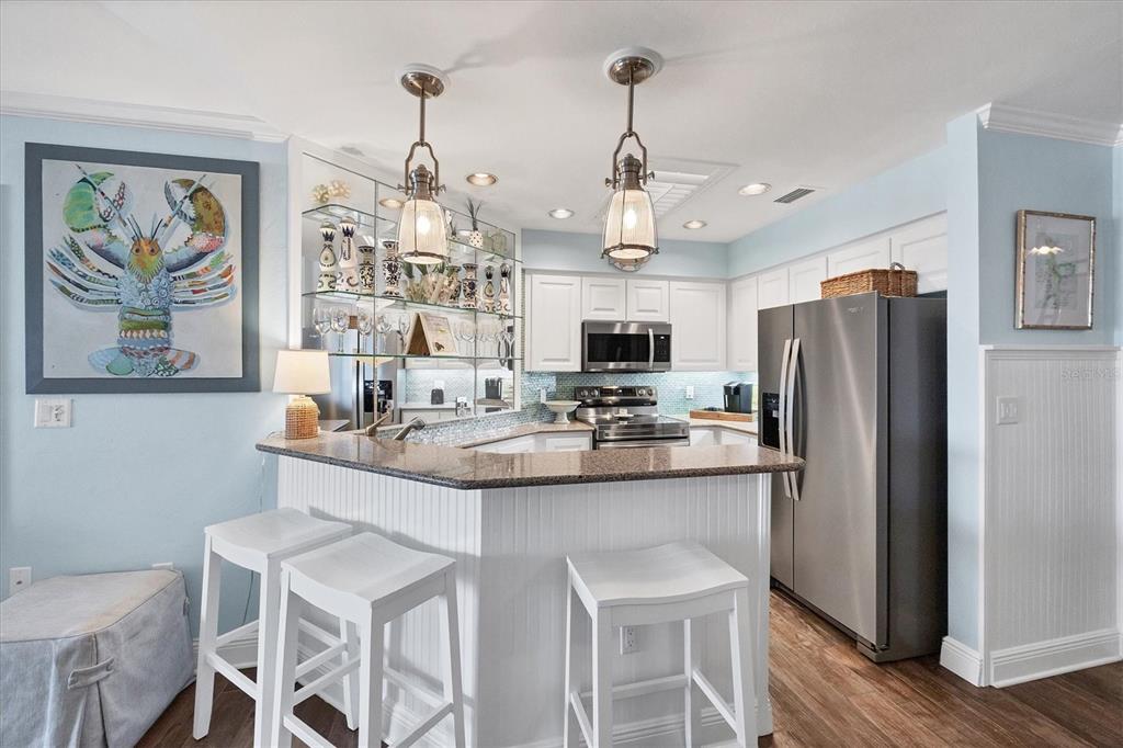 5854 Gasparilla Road, Unit MV20 Boca Grande, FL 33921 - Photo 6 of 49 a kitchen with stainless steel appliances kitchen island granite countertop a sink a refrigerator and chairs