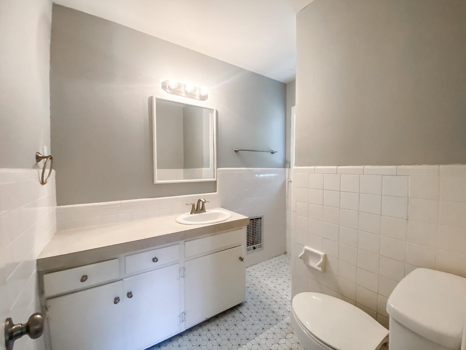 4010 47th Street Lubbock, TX 79413 - Photo 13 of 20 a bathroom with a toilet a sink a mirror and a window